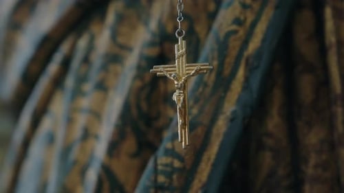 golden crucifix hanging softly against ornate church fabric