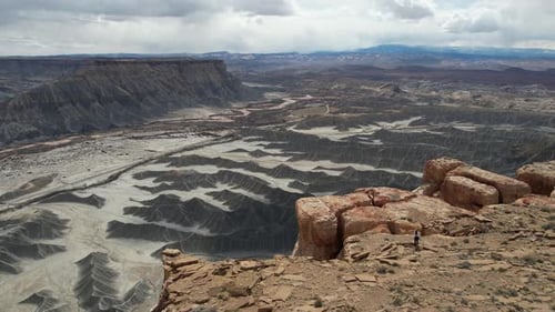 Aerial View of Female Person Walking on Top fo The Cliff Above Deep Gray Desert Canyon, Utah USA