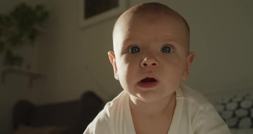 Closeup Portrait of Little Baby Boy Trying to Stand on All Fours and Crawl on a Bed