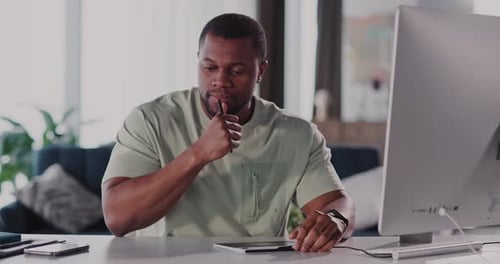 A Focused Man Working Diligently at His Home Office Using a Digital Tablet Device