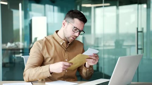 Worried Man Reads Documents at His Desk