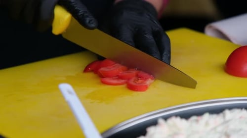 Gloved Hands Slicing Fresh Tomatoes on Yellow Board