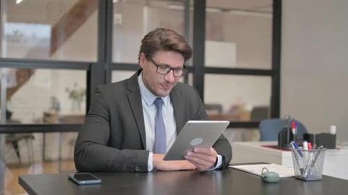 Middle Aged Businessman Doing Video Chat on Tablet in Office