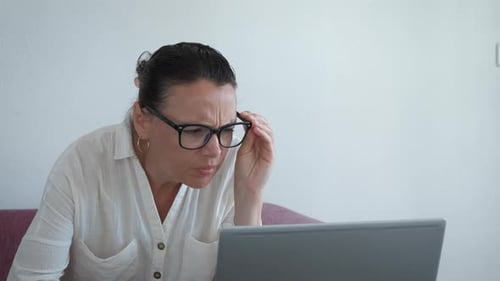 Frau blinzelt müde Augen am Laptop