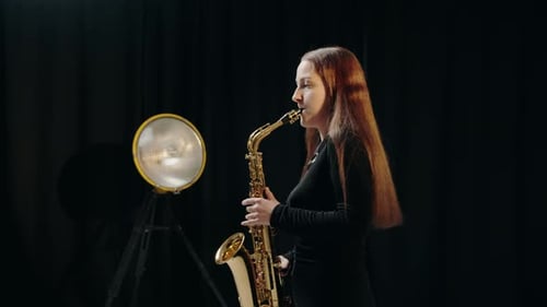 Woman Plays Saxophone in Dark Studio