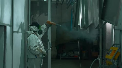 Factory Worker Coating Metal Panels with Spray Gun