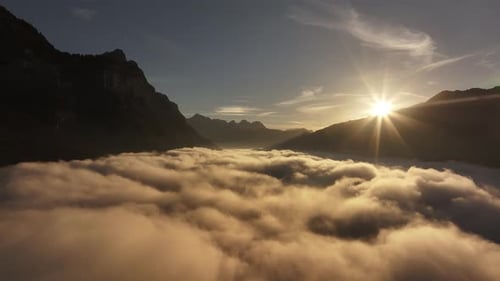 Sunrise over cloud-covered Walensee framed by Swiss Alps peaks in a serene mountain landscape