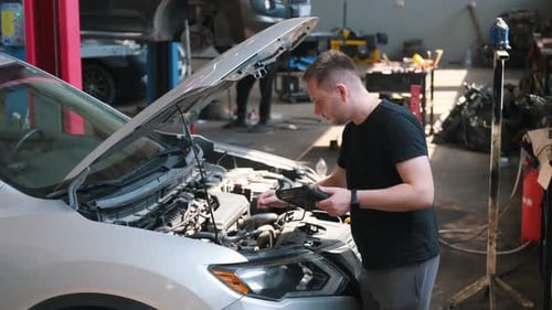 Mecánico de automóviles profesional que trabaja en un servicio de reparación de automóviles con tableta. Diagnóstico informático en el garaje