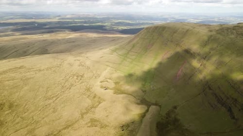 Cloud shadows passing over Brecon Beacons Llyn y Fan Fach green mountain valley aerial forward movin