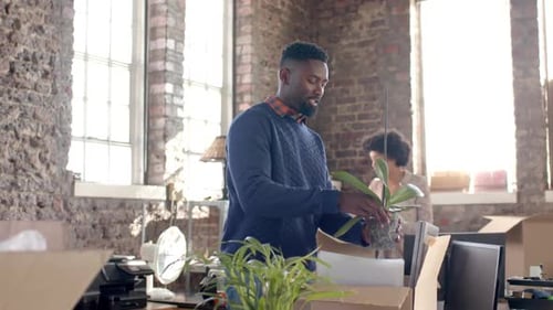 Diverse colleagues unpacking boxes with documents and office items in creative office in slow motion