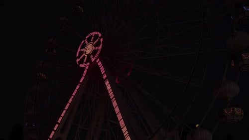 Rotating Ferris Wheel In Amusement Park At Night