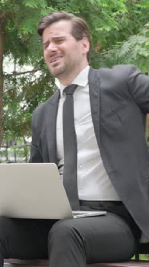Man in Suit Works on Laptop, Back Pain