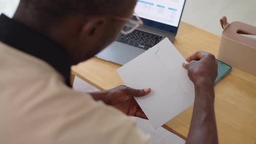Man Opening Letter from Bank with Credit Card