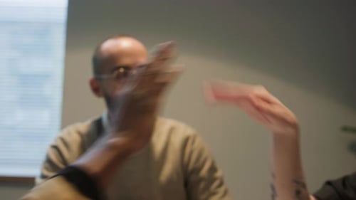Close-up of Three Young Coworkers Giving High-fives to Each Other