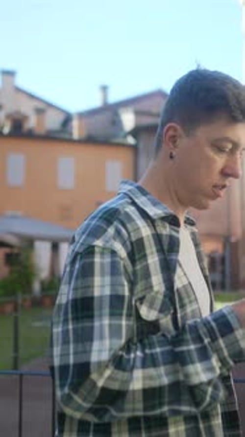 A Young Man is Using a Phone Outdoors in an Urban Area Checking Messages and Browsing the Internet