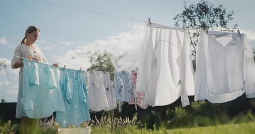 Woman Hanging Laundry on Clothesline Outside on Sunny Day