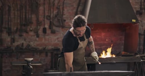 Blacksmith, hammer and man on anvil in workshop for forging iron, steel or metal