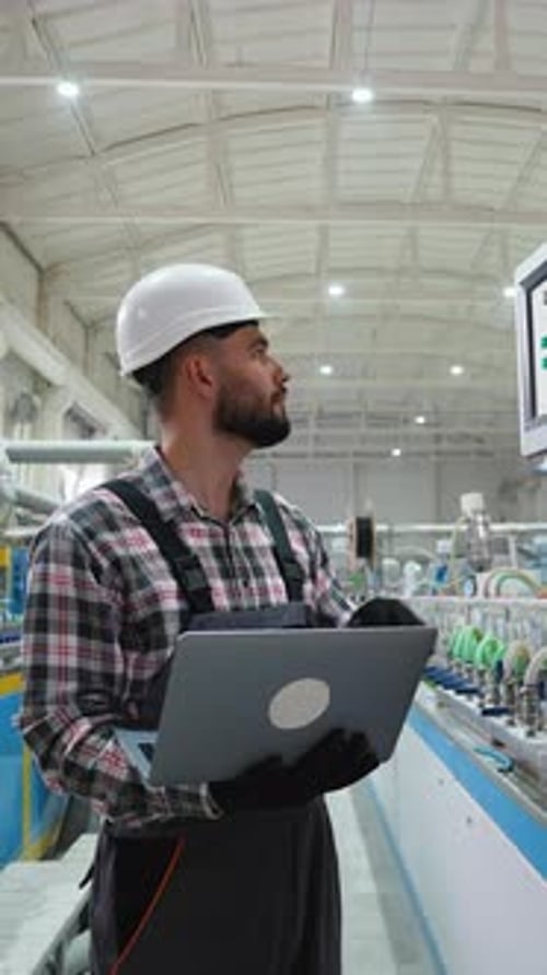 Industrial Engineer Using Laptop and Touchscreen in Factory