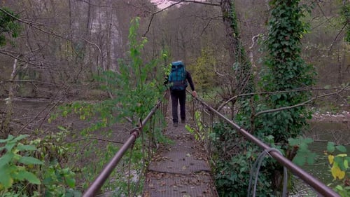 man backpaking on the rope suspension bridge