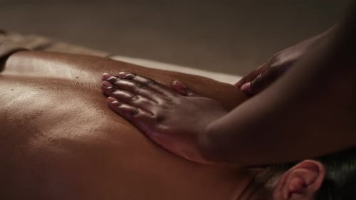 Close-up of Hands of Unrecognisable Masseuse Massaging Back of Young Woman