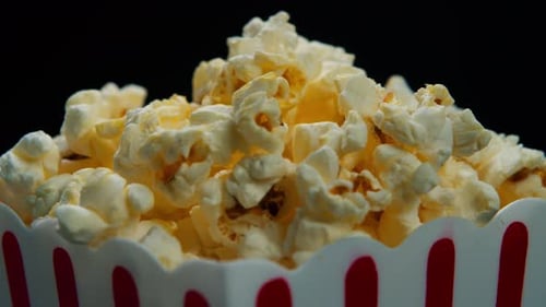 Air Popcorn in a Red and White Striped Bucket Rotates on a Black Background