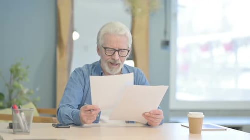 Old Man Celebrating Win while Reading Documents in Office