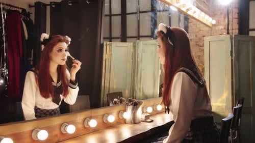 Beautiful Young Woman Applying Makeup at Vanity