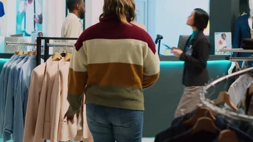 Retail Store Customer Examining Clothes on Racks