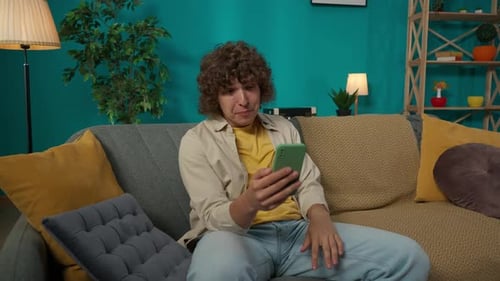 Smiling Young Adult Video Chatting on Smartphone at Home