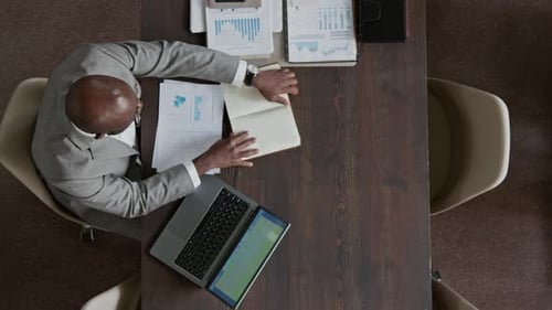 Top View of Male Office Worker Researching Data for Report on Laptop