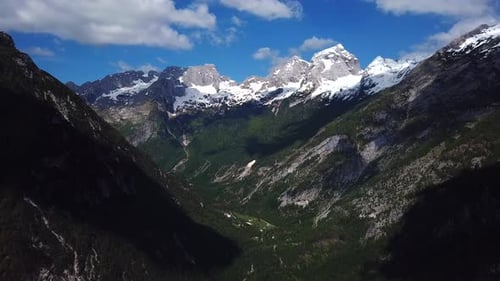 Forward drone shot of slovenian mountains, on a sunny day with some clouds