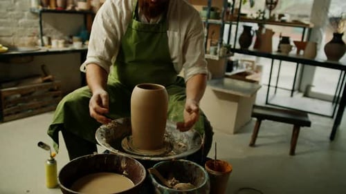 Potter Shaping Clay on Pottery Wheel in Studio