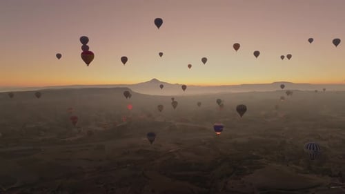 Drone view of hundreds of colorful hot air balloons soaring at sunrise in Cappadocia