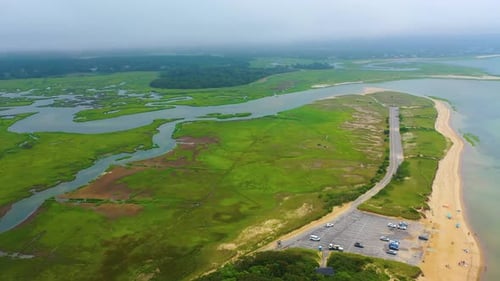 Drone Flyover of Sandy Beach, Marshland, and Ocean Coastline on Cloudy Day