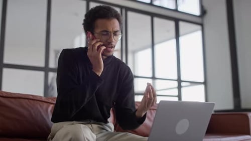 Young Adult on Phone with Laptop on Couch
