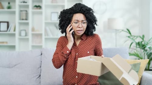 Upset Woman on Smartphone With Delivery Box