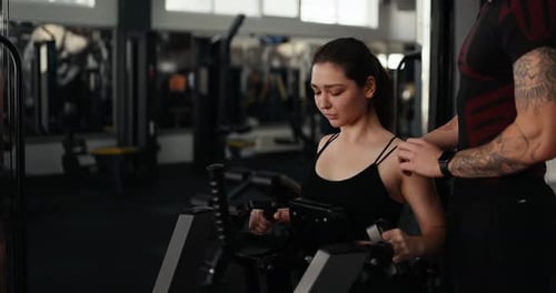 Woman Working Out at Gym With Trainer