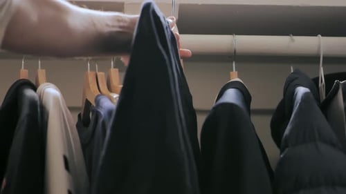 Hand selects clothes from closet wardrobe, close up