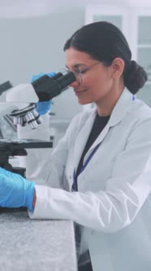 Woman Scientist Using Microscope in Bright Laboratory