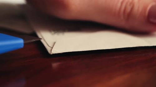 Close-up of hands opening a letter with a stationery knife.