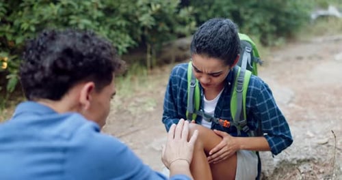 Man Examines Woman's Injured Knee on Forest Trail