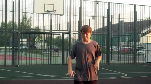 Boy Playing Basketball He is Holding a Ball and Standing on a Court It is an Open Place with