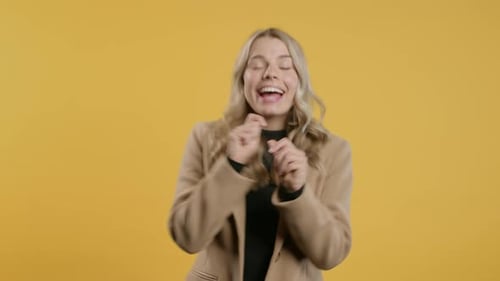 Woman Dancing with Joy on Yellow Background