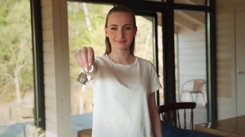 Woman Holding Keys to New Home Indoors