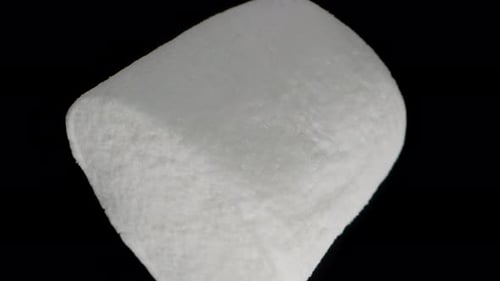 Lone White Marshmallow Rotating and Falling on Black Isolated Background. Macro Zoom. Slow Motion.