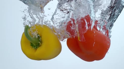 Bright Colorful Peppers Dropping into Water in Slow Motion