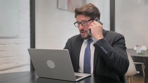 Professional Man Working On Laptop Talking on Phone