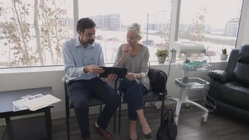 Doctor shows patient digital tablet during consultation at hospital in winter