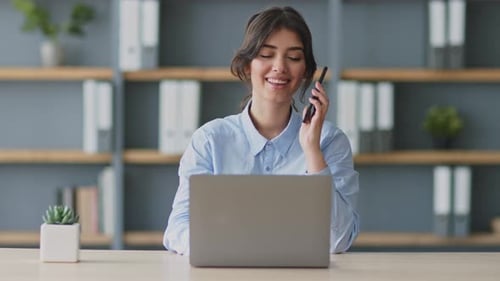 Smiling Woman Talking on Cell Phone at Desk