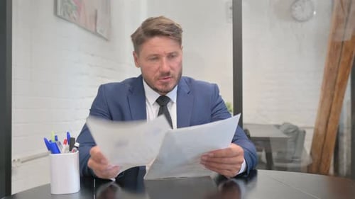 Man in Suit Reviews Documents in Office